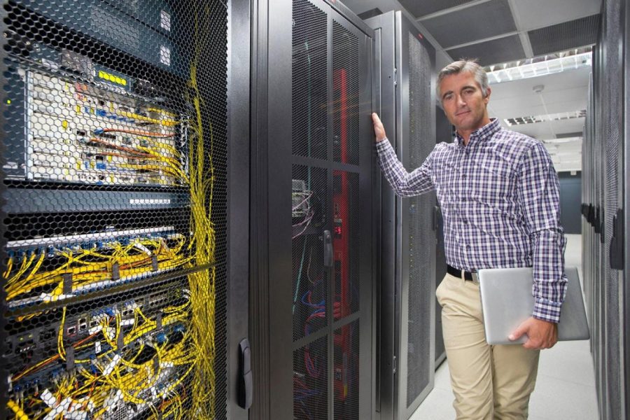 Data centre engineer standing beside server cabinets in a UAE hosting facility
